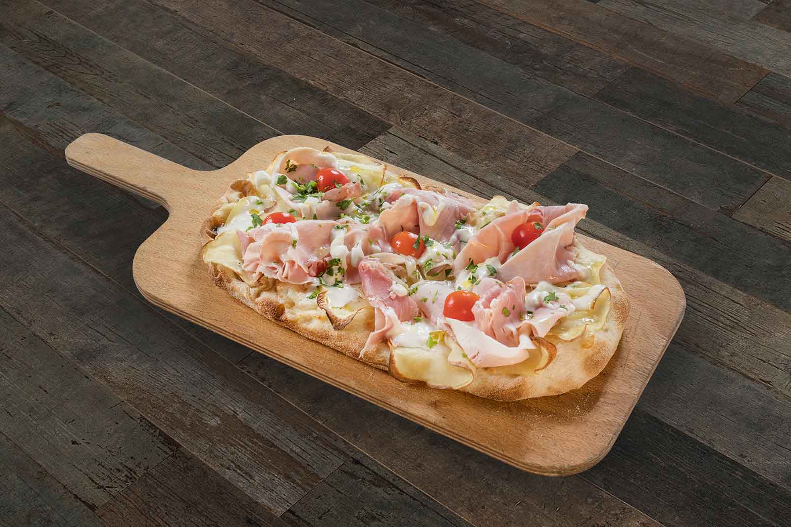 Pinsa pinsami farcita con mozzarella, patate tagliate sottili, cotto, stracciatella, pomodorini e prezzemolo