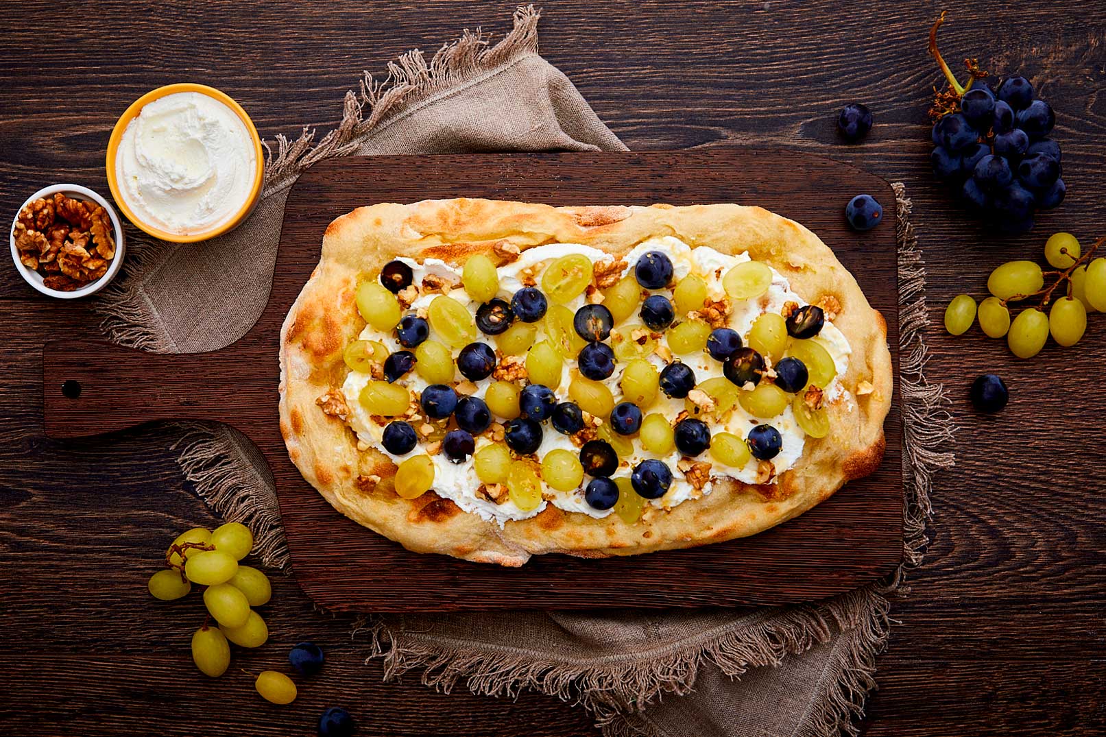 Pinsa integrale con ricotta, uva bianca, uva rossa, noci, miele, timo e zucchero a velo