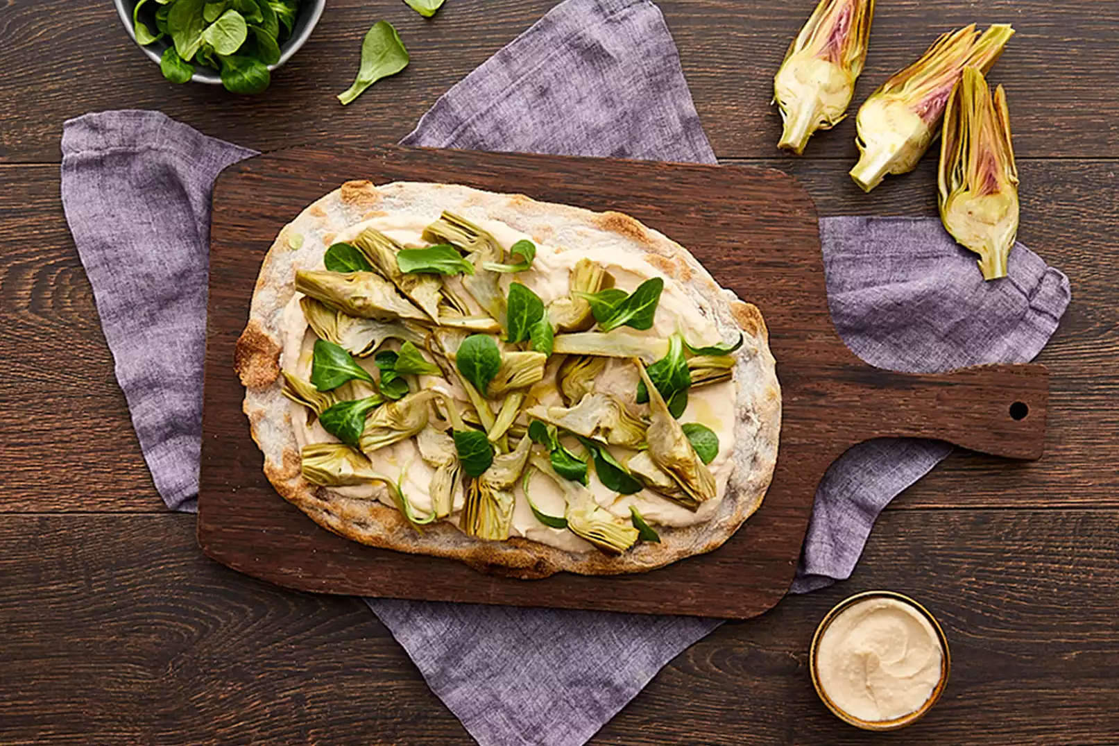 Pinsa pinsami integrale guarnita con carciofi, hummus, fagioli cannellini e valeriana