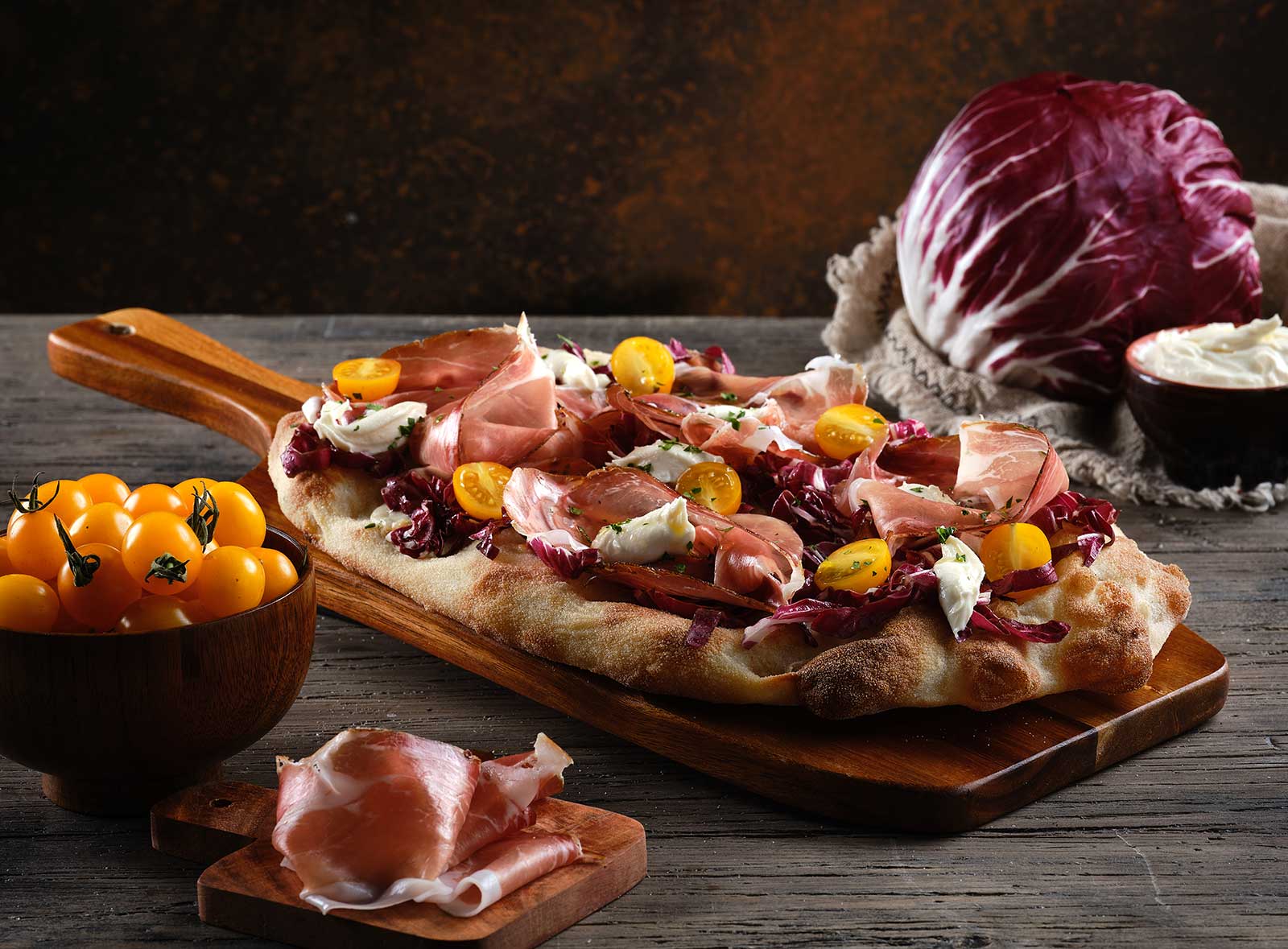 Pinsa con mozzarella, radicchio, speck, taleggio, pomodorini gialli e prezzemolo