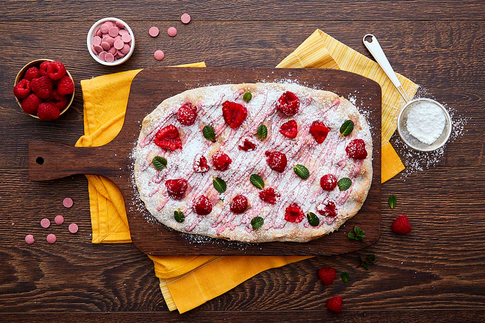 Pinsa pinsami farcita con cioccolato ruby, lamponi, foglioline di menta e zucchero a velo