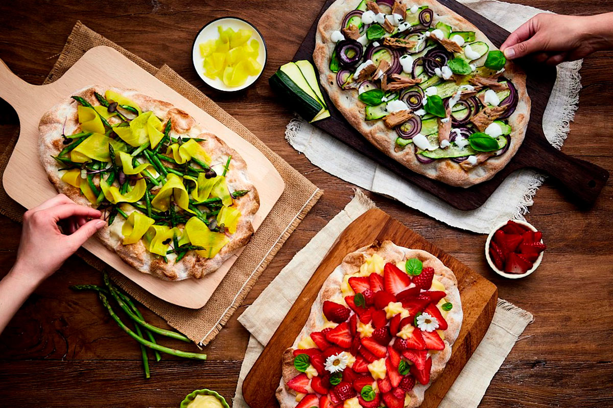 Pinsa Party con pinsa farcita con fragole, menta e crema; una con asparagi e mango; una con cipolla, tonno, basilico e zucchine