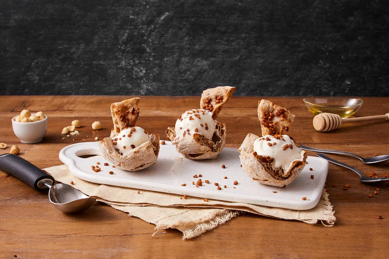 Tre quadrati di pinsa pinsami integrale piegati concavi con dentro gelato, granella e triangolini pinsa integrale glassati