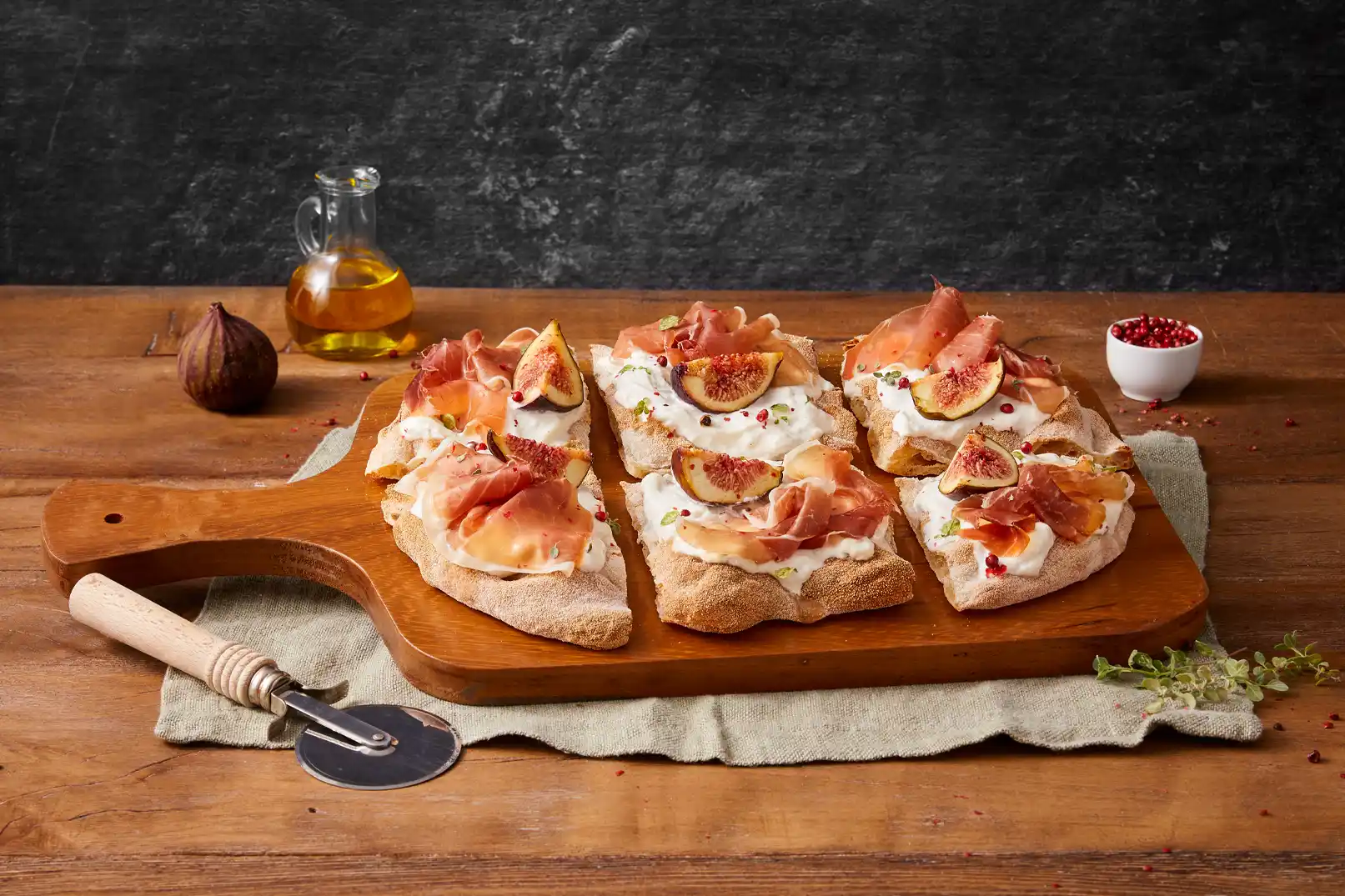 Pinsa pinsami tagliata a quadratini farcita con stracciatella, crudo, fichi, pepe rosa e maggiorana