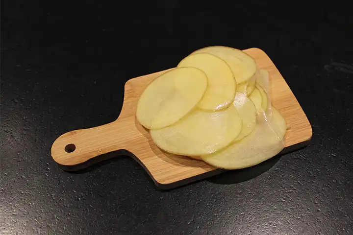 Schneide die Kartoffel mit einer Mandoline in dünne Scheiben