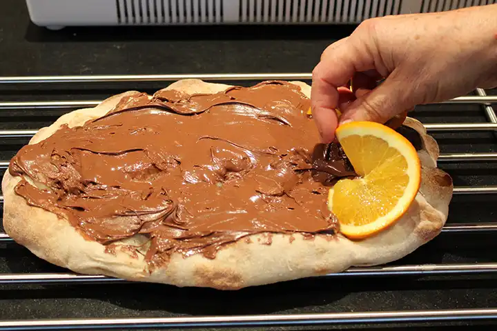 Schneide die Orange in dünne Scheiben und lege sie darauf
