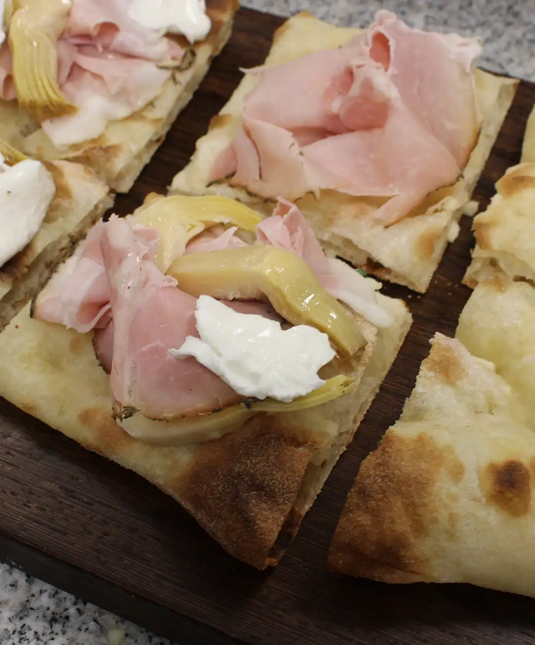 Auf jedes Stück gib einige Scheiben gegrillten Schinken, die Artischocken und die Burrata