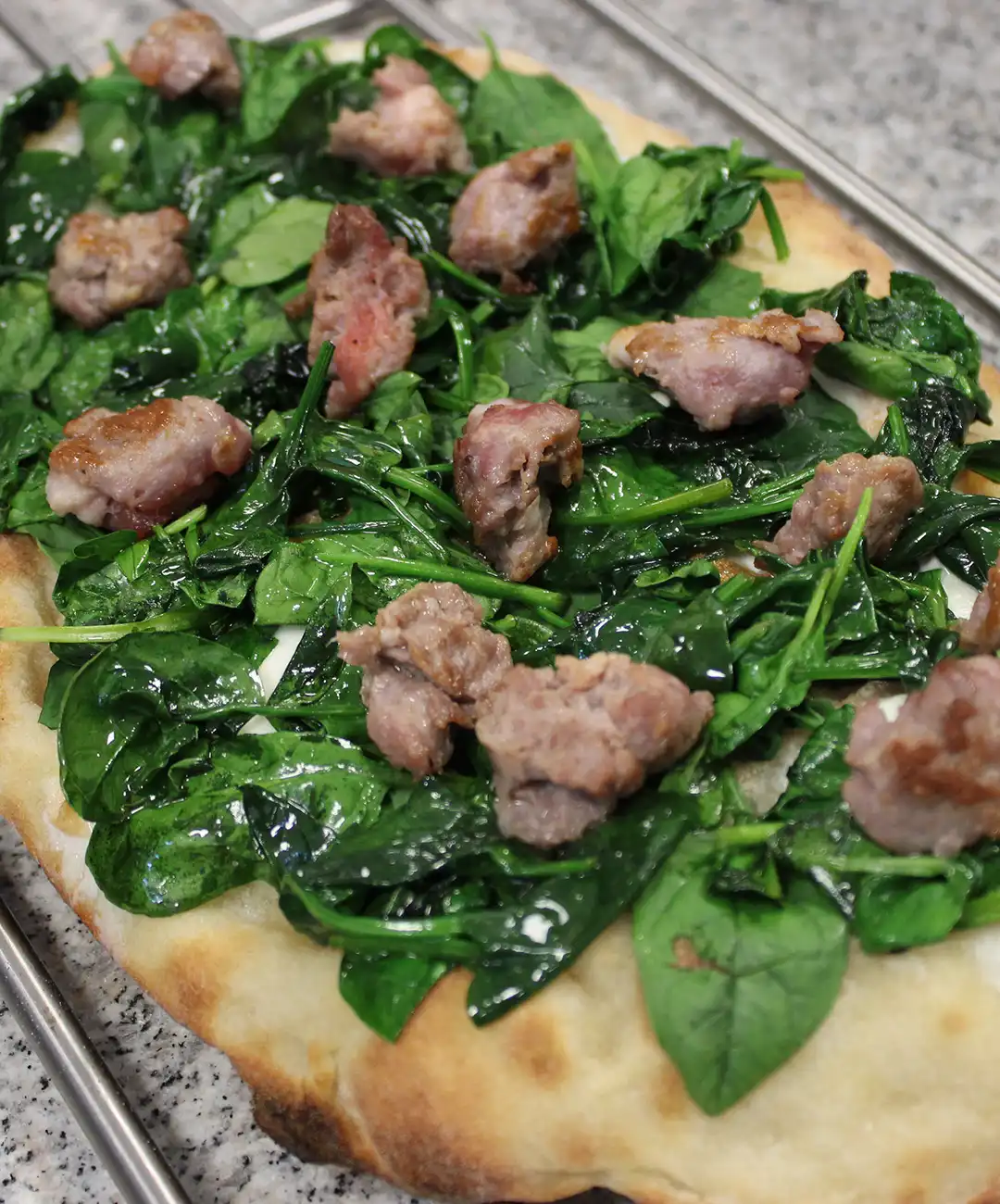 Belegen Sie mit Mozzarella, Spinat und Salsiccia.
