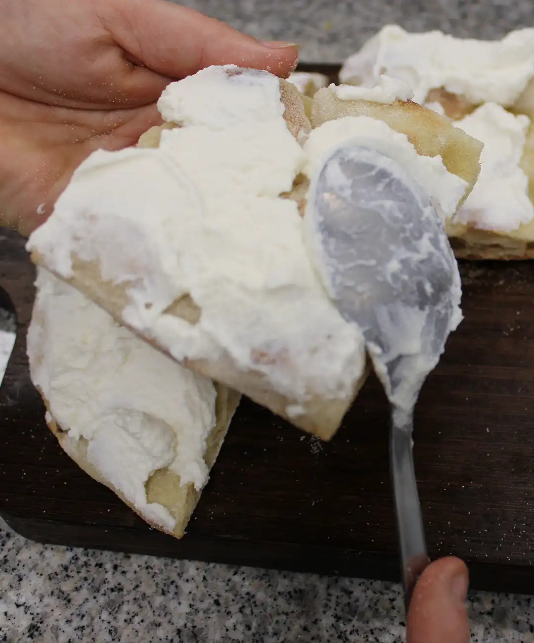 Schneide den Lachs in Herzform, nimm die Pinsa aus dem Ofen und schneide sie in 6 Stücke. Verteile den Frischkäse
