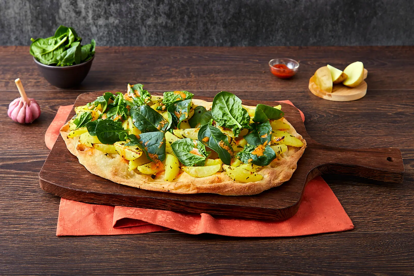 Pinsa garniert mit Kartoffeln, Petersilie, Spinat, Kümmel, Harissa-Sauce und Senf