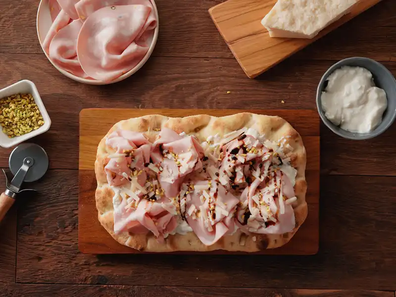 Aggiungi l'aceto balsamico e il Parmigiano Reggiano per completare la pinsa