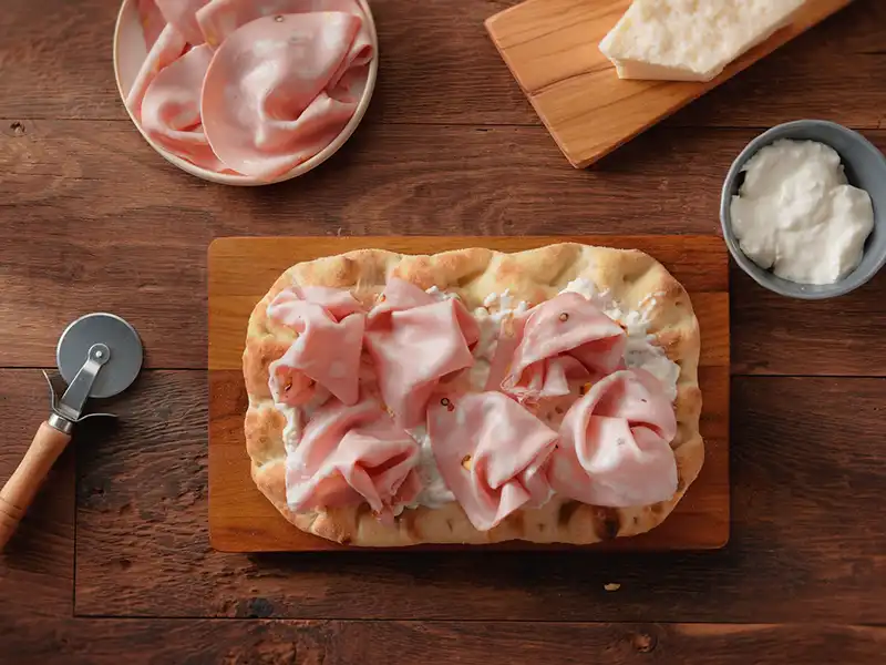 Stendi lo squacquerone e la mortadella sulla base pinsa